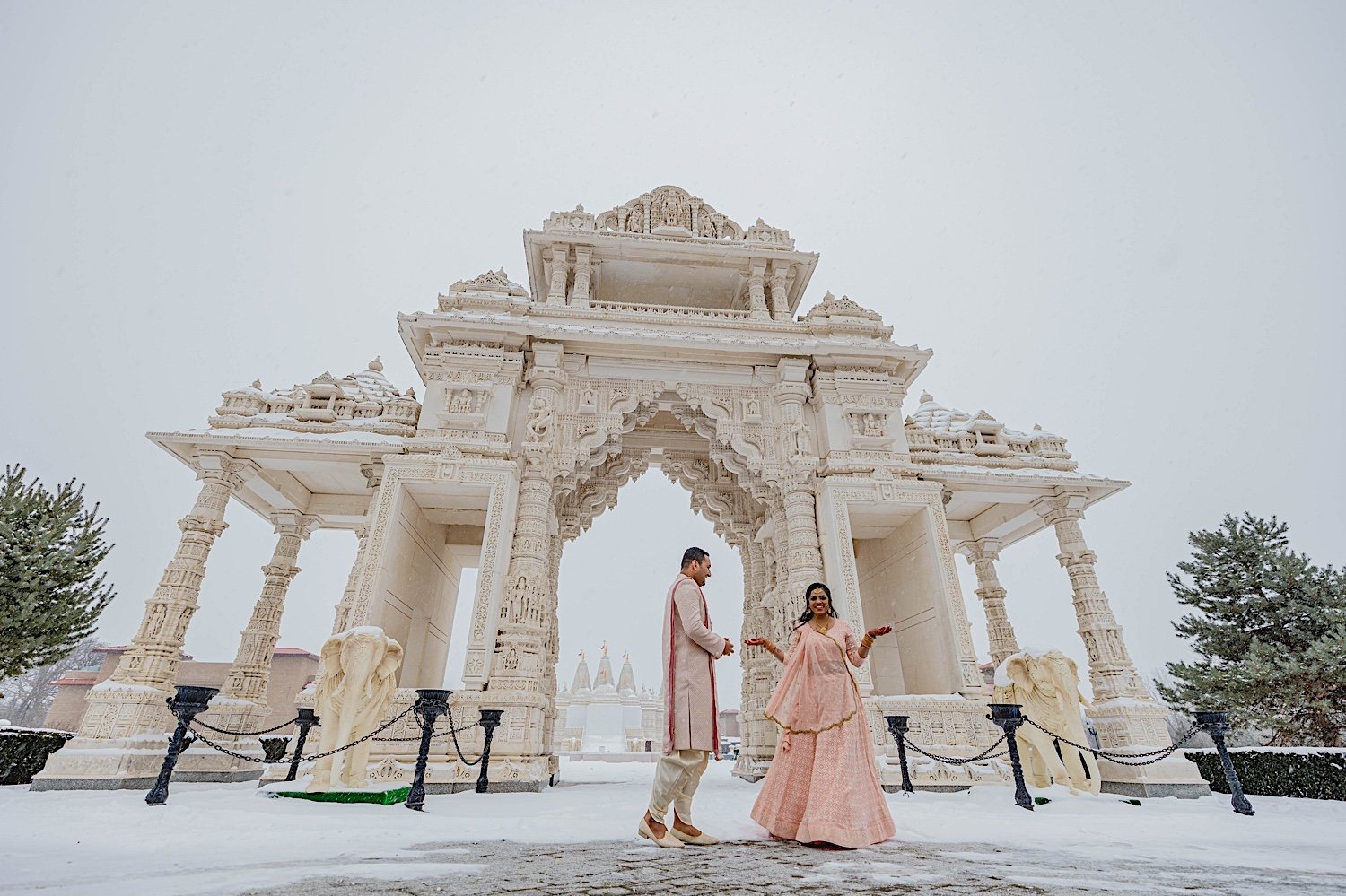 Bride and groom dance in front of snow covered Hindu temple