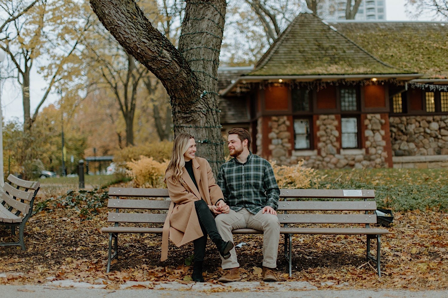 Couple smiles and sit on a bench together in a park