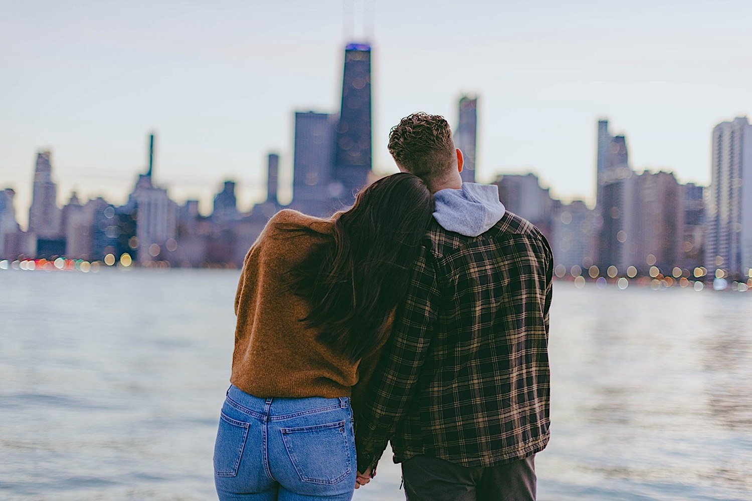 Couple stand next to each other at North Avenue beach for their engagement session with Chicago in the background