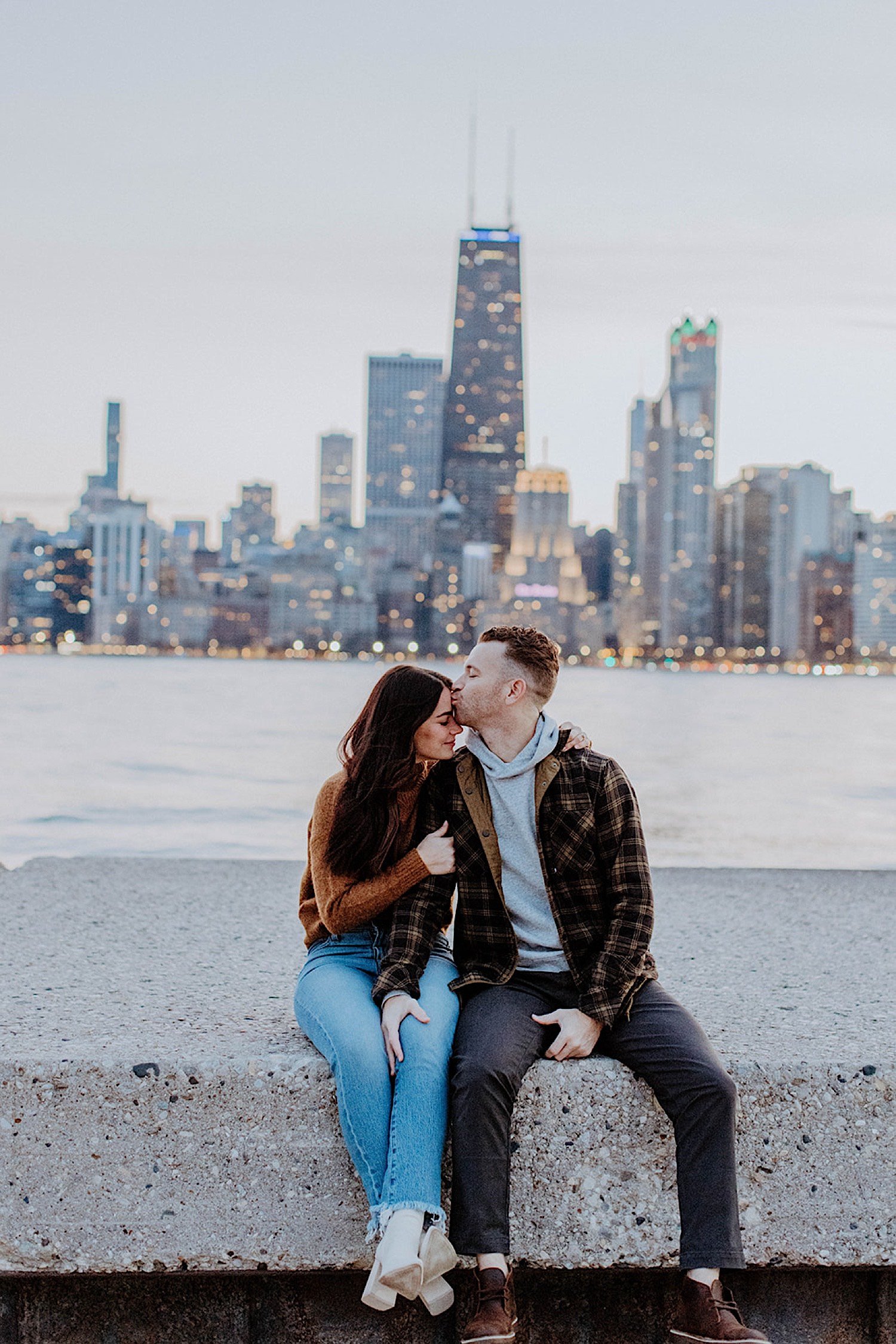 Couple kiss after their North Avenue Beach engagement with the Chicago skyline behind them