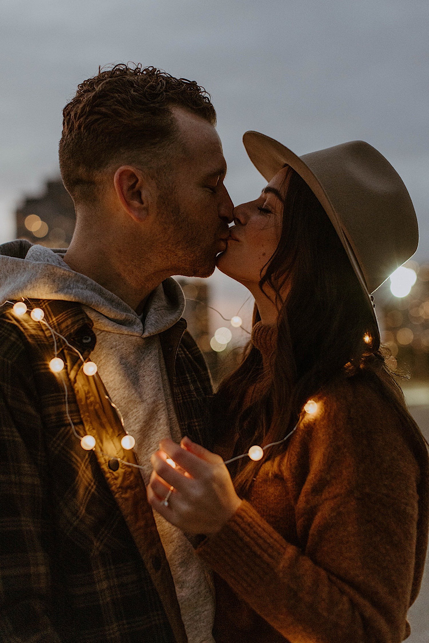 Couple kiss while wrapped in string lights