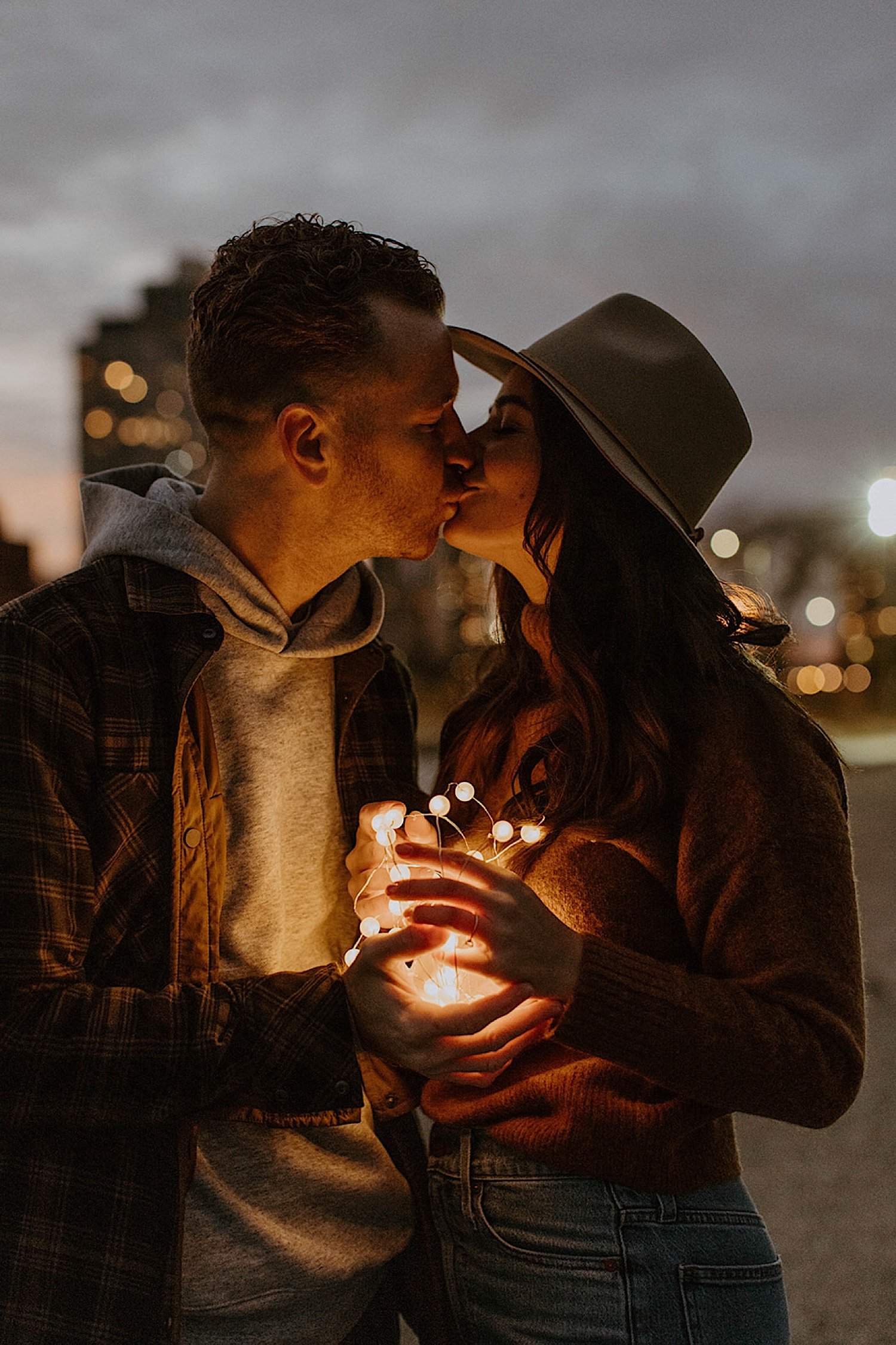 Couple kiss while holding string lights