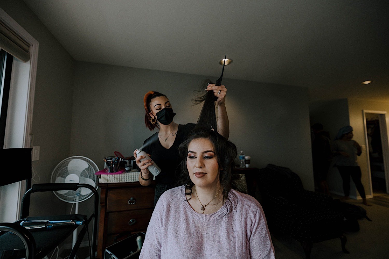 Hair stylist works on bride's hair before wedding day in hotel room