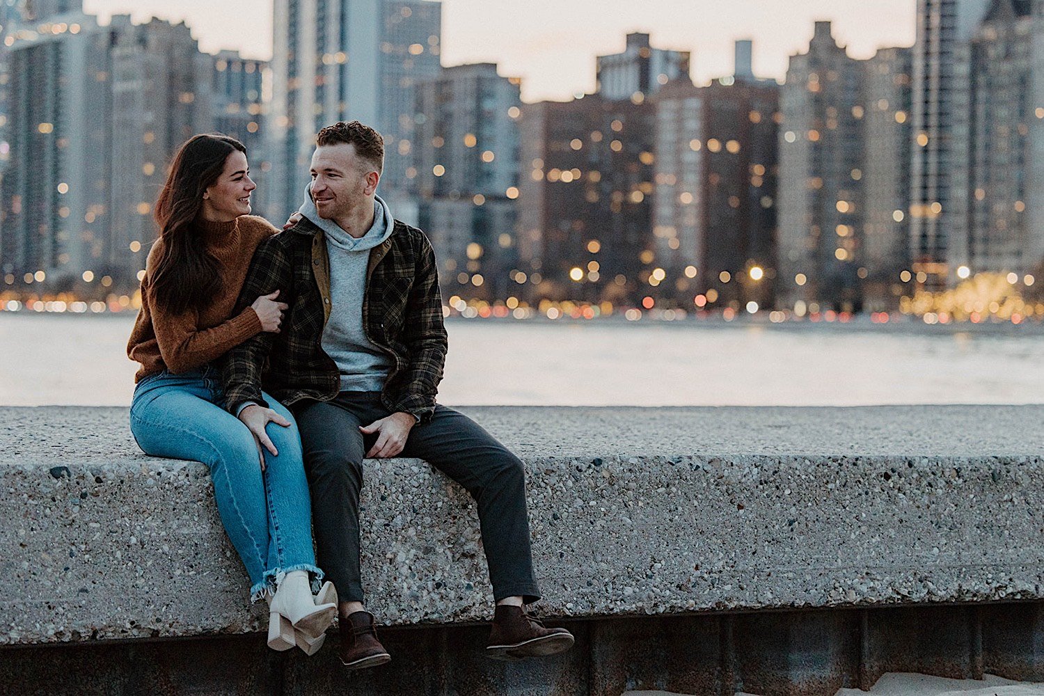 Couple sit together at Chicago's North Avenue Beach with the city skyline in the background