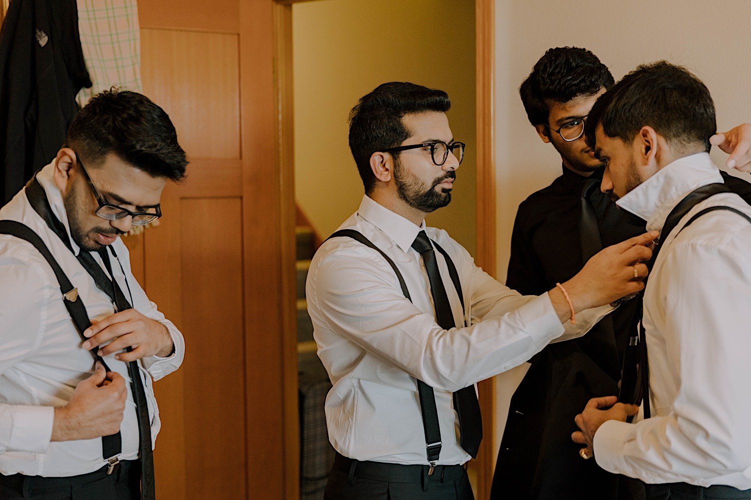 Groomsmen assisting one another with their ties as they get ready for a wedding