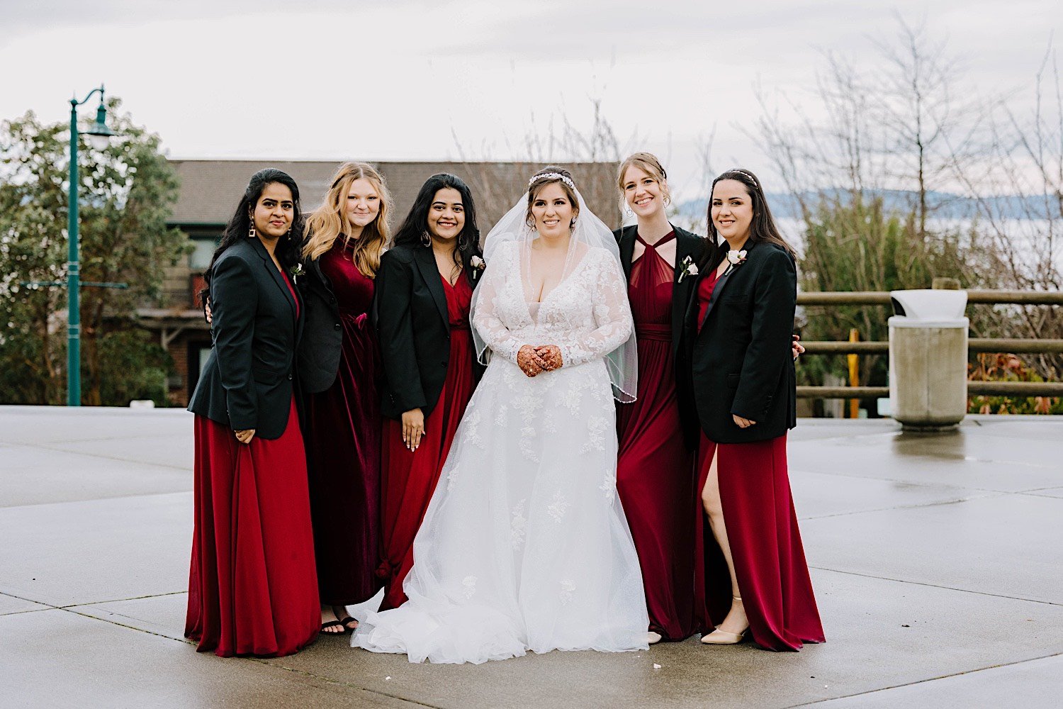 Bride and bridesmaids pose together and smile at the camera outside the Rosehill Community Center