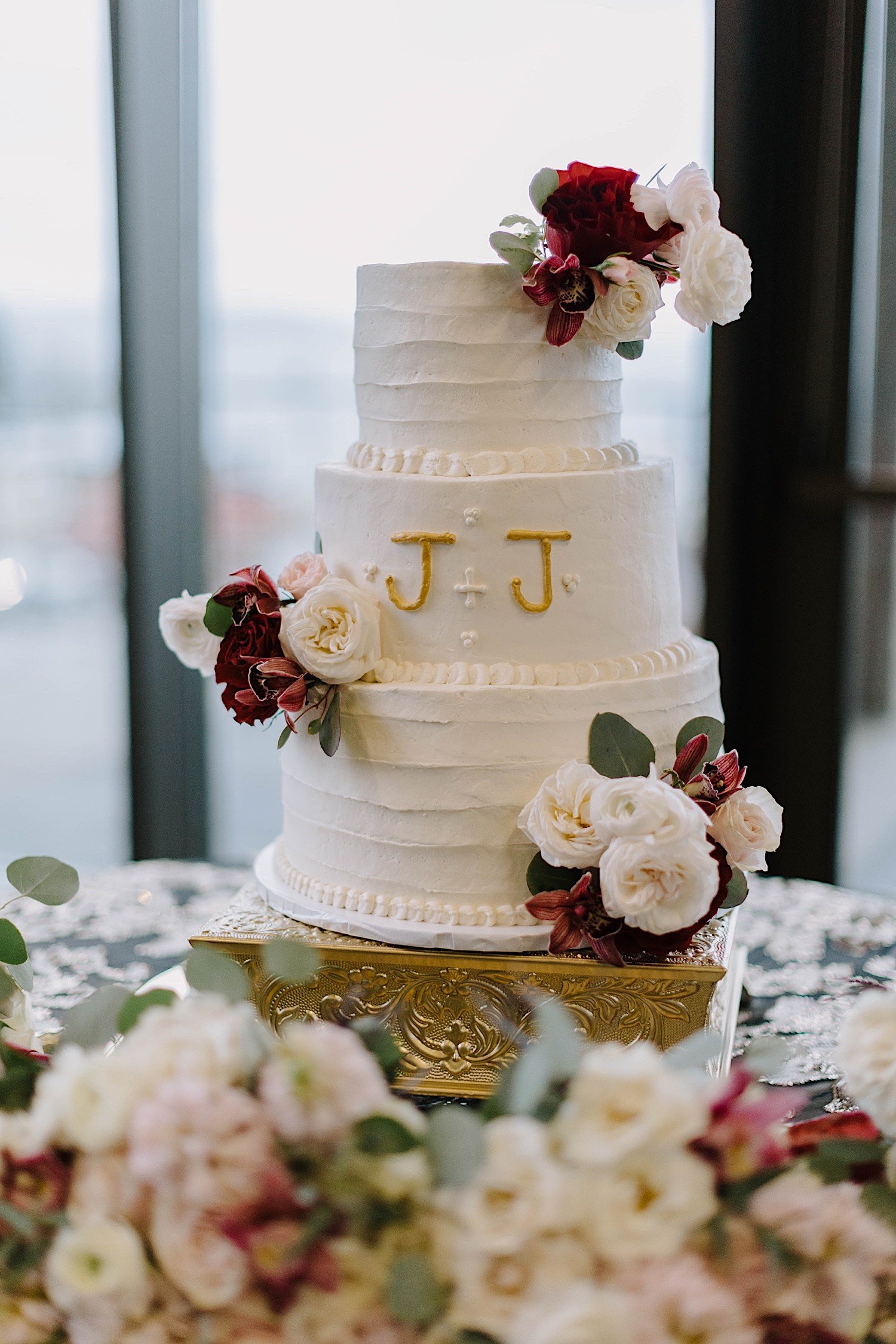 Wedding cake with initials J + J on the side surrounded by flowers