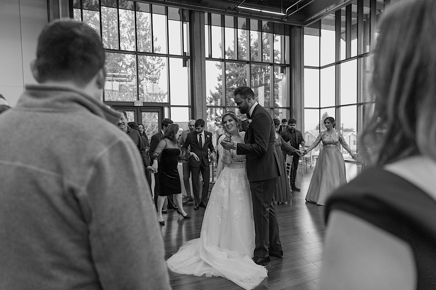 Black and white photo of bride and groom sharing their first dance together at Rosehill Community Center surrounded by their friends and family