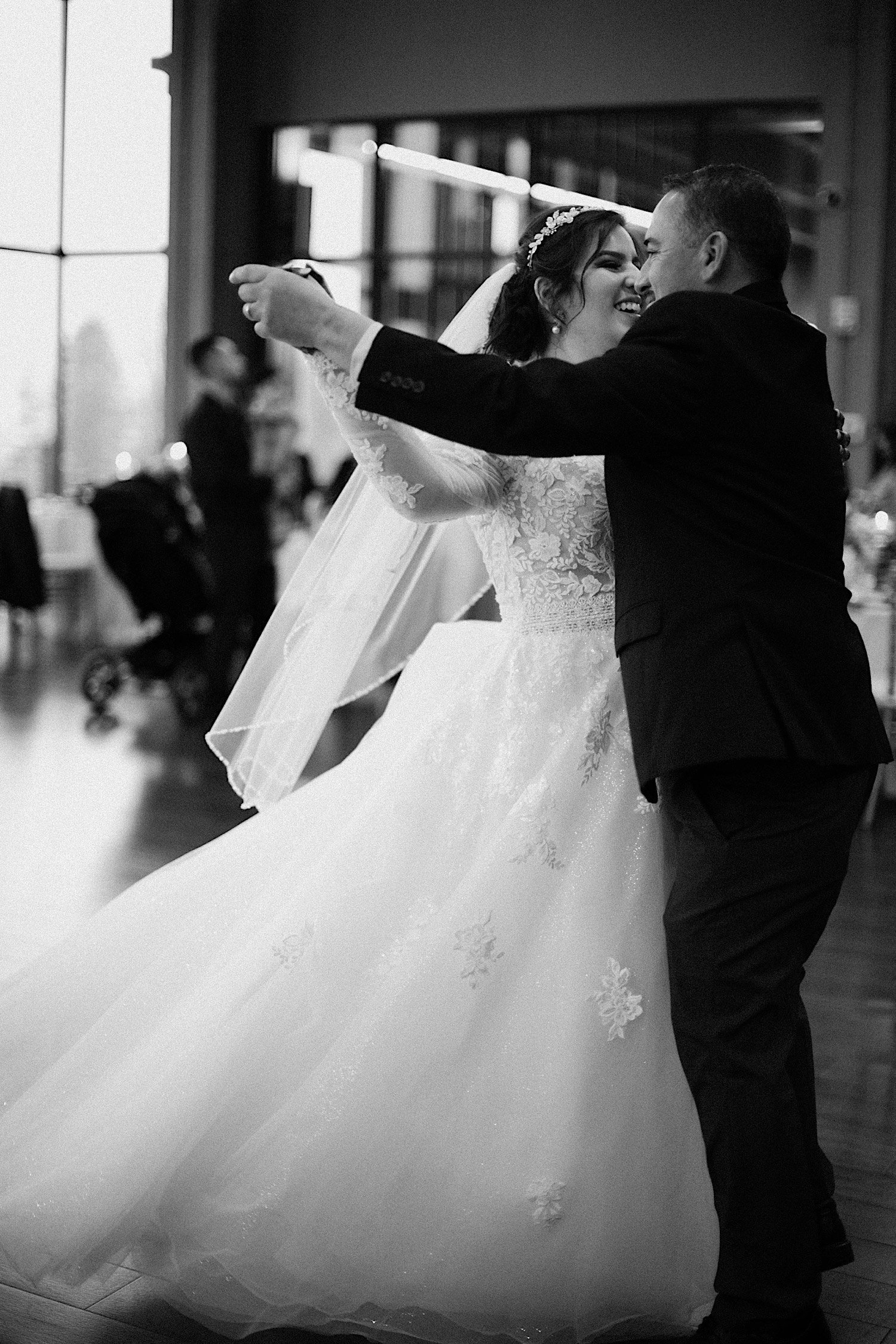 Black and white photo of bride and her father smiling and dancing together
