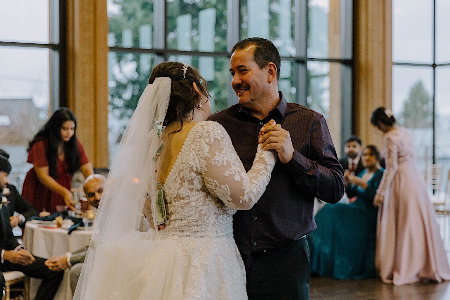 Bride shares a dance with her father as guests watch in the background