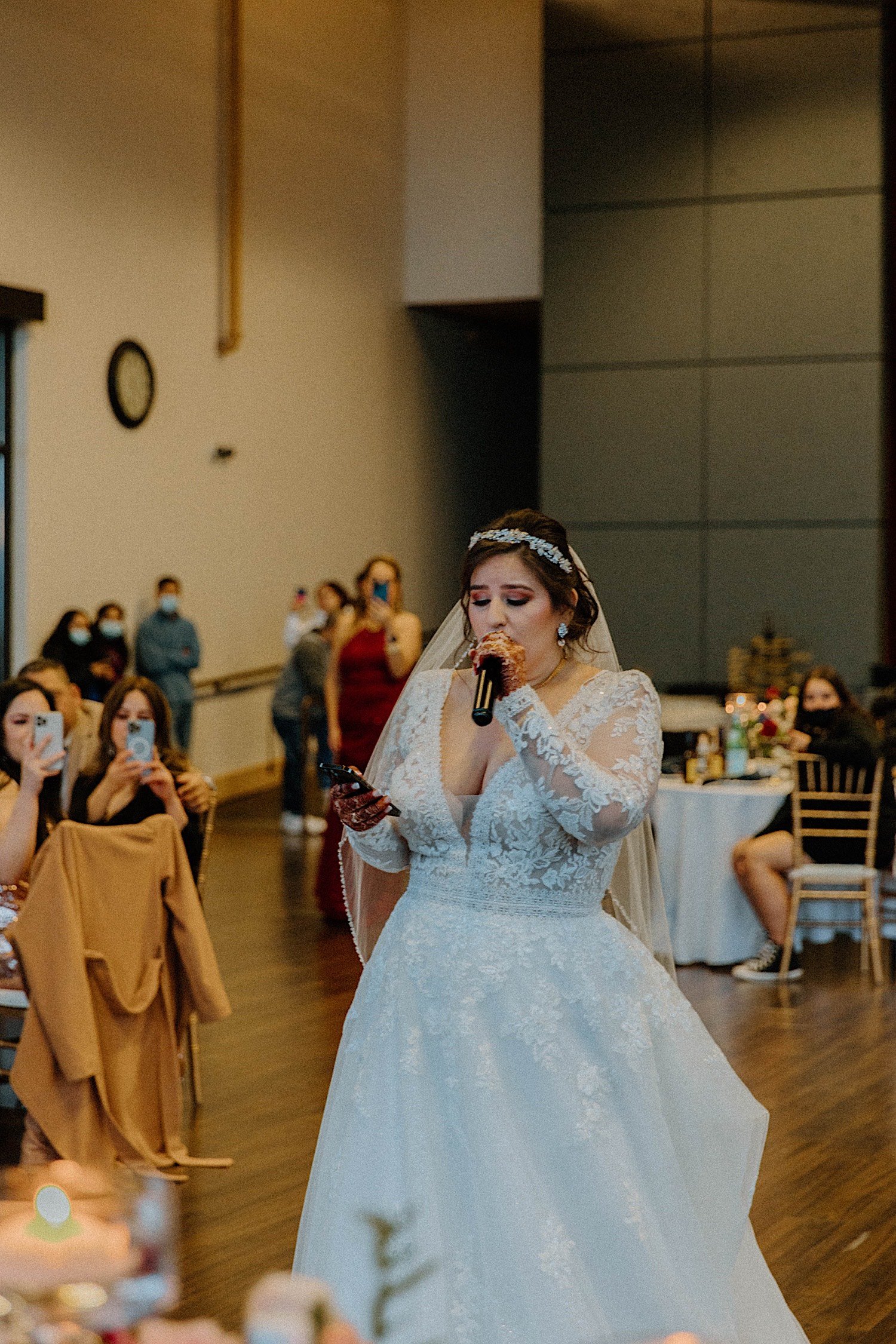 Bride sings to groom while guests watch and record in the background