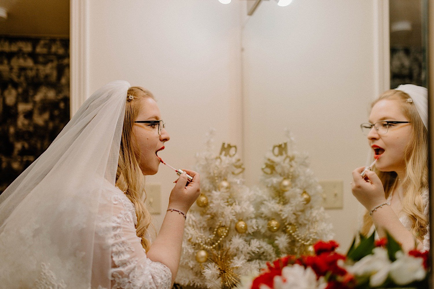 Bride puts lipstick on in the mirror while wearing her wedding gown