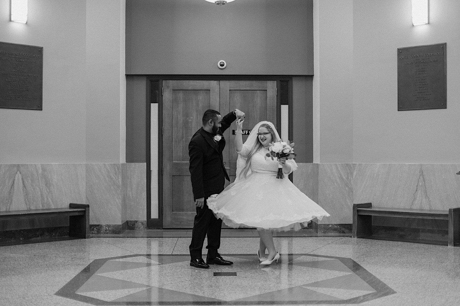 Black and white photo of newly weds dancing in waiting area of their venue