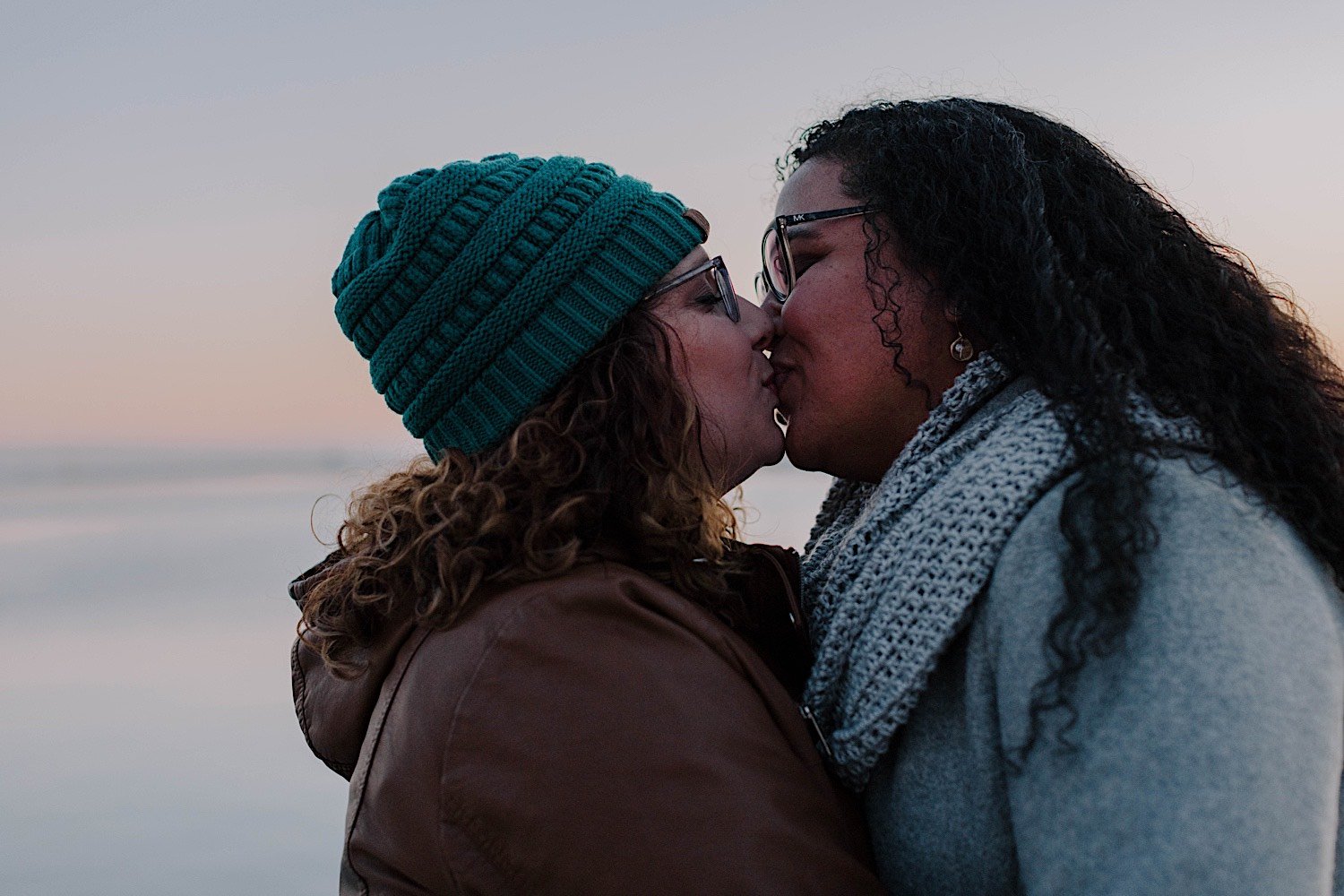 Couple kiss during their museum campus engagement in front of Lake Michigan at sunrise
