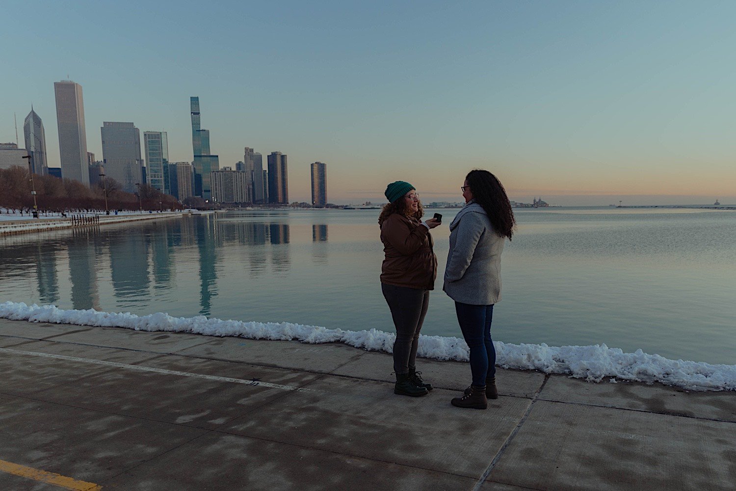 Couple looking at one another during their museum campus proposal with a snowy Lake Michigan behind them at sunrise