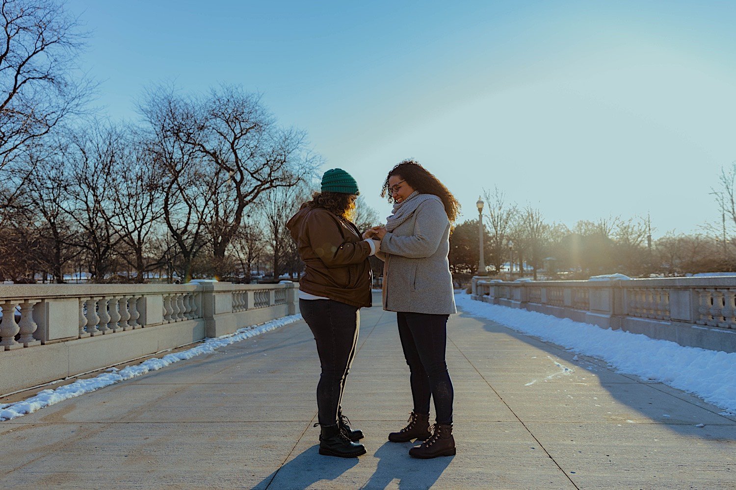 Couple standing together putting on an engagement ring on a bridge at Chicago's museum campus