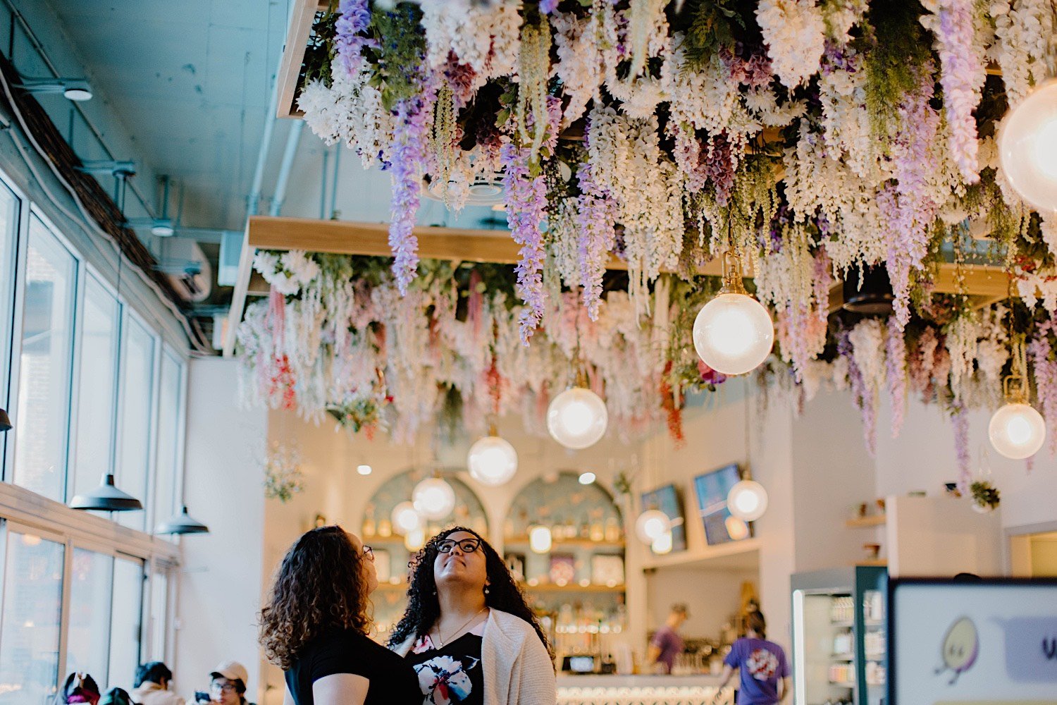Couple stand together and look at flowers above them at Wake N Bacon restaurant in Chicago