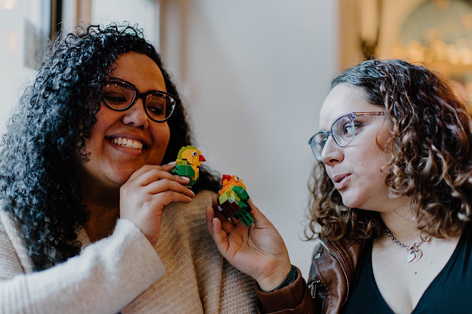 Couple holding Lego parrots playing with one another and smiling at eachother