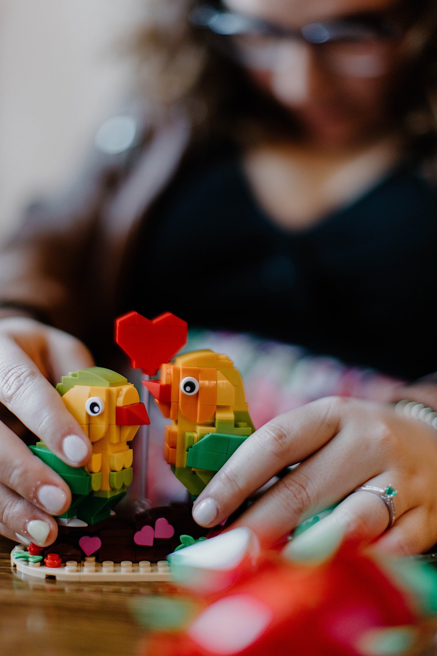 Lego parrots with a Lego heart are posed next to each other by a newly engaged couple