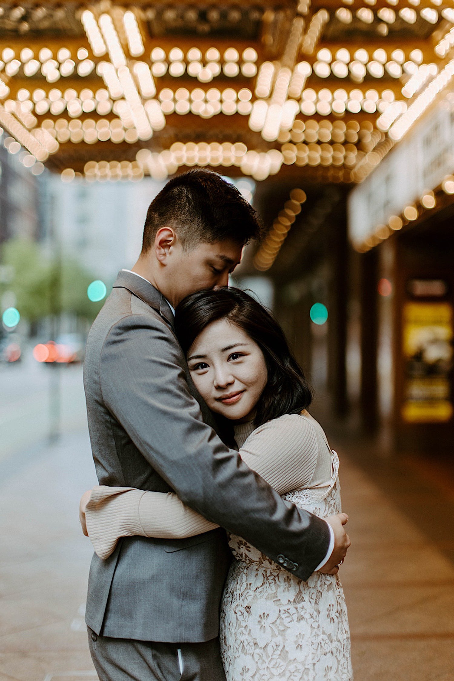 Couple embrace and look at the camera underneath the Chicago theatre's lights