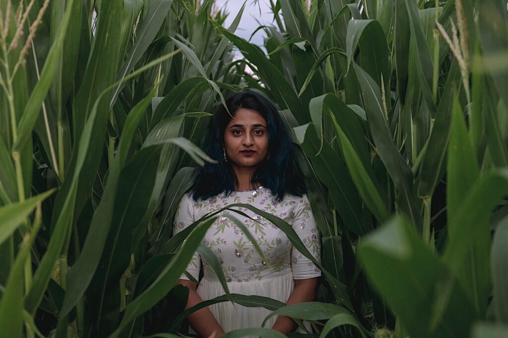 Portrait of a woman looking at the camera in the middle of a cornfield.