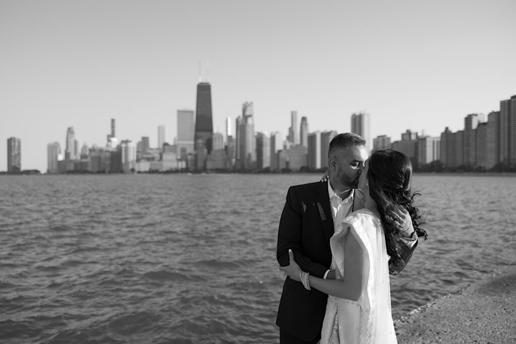 Black and white photo of a couple kissing during their elopement with the Chicago skyline and Lake Michigan behind them