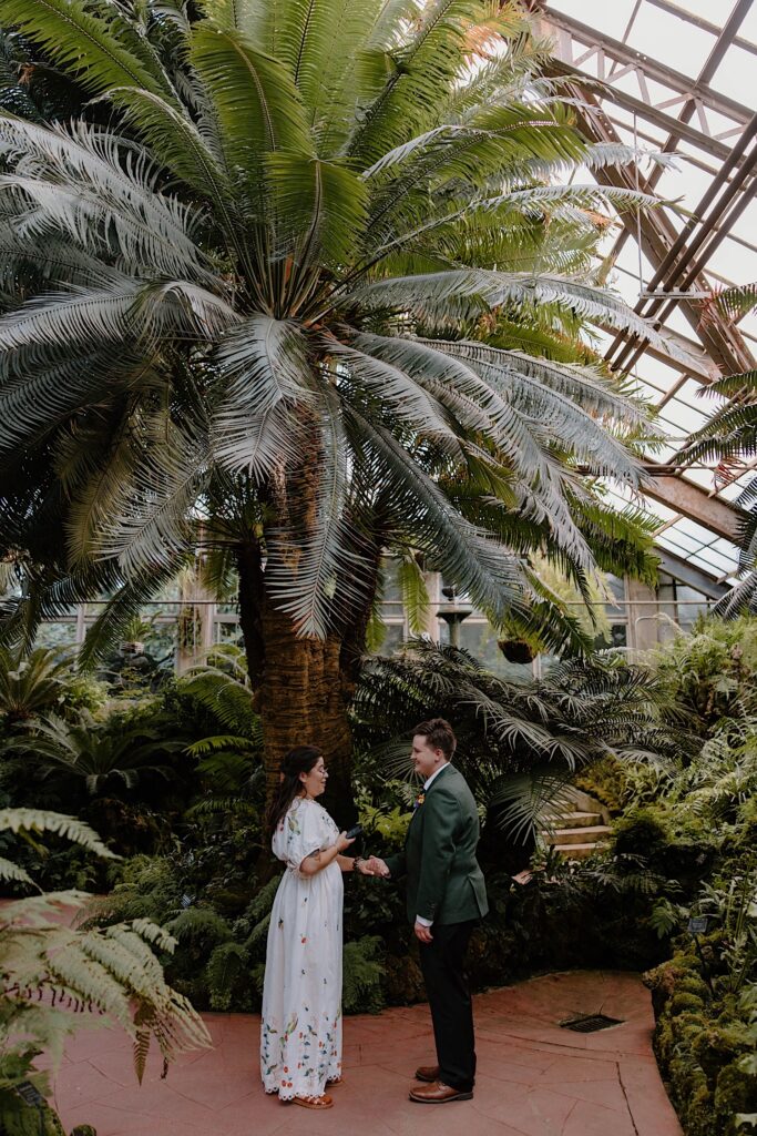 A couple reads their vows to one another during their elopement in an arboretum 